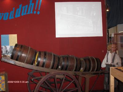 878117 Afbeelding van een transportkar met vaatjes azijn op de zojuist geopende tentoonstelling 'Vodduh', in het ...